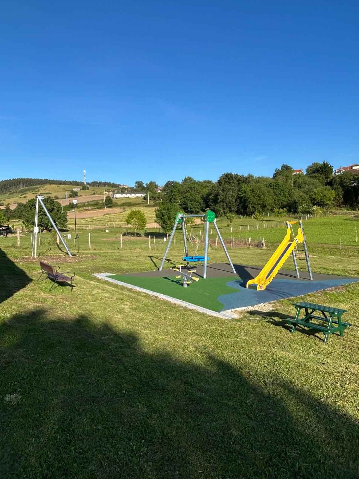 Un parque infantil con tobogán, columpios y una mesa de picnic.