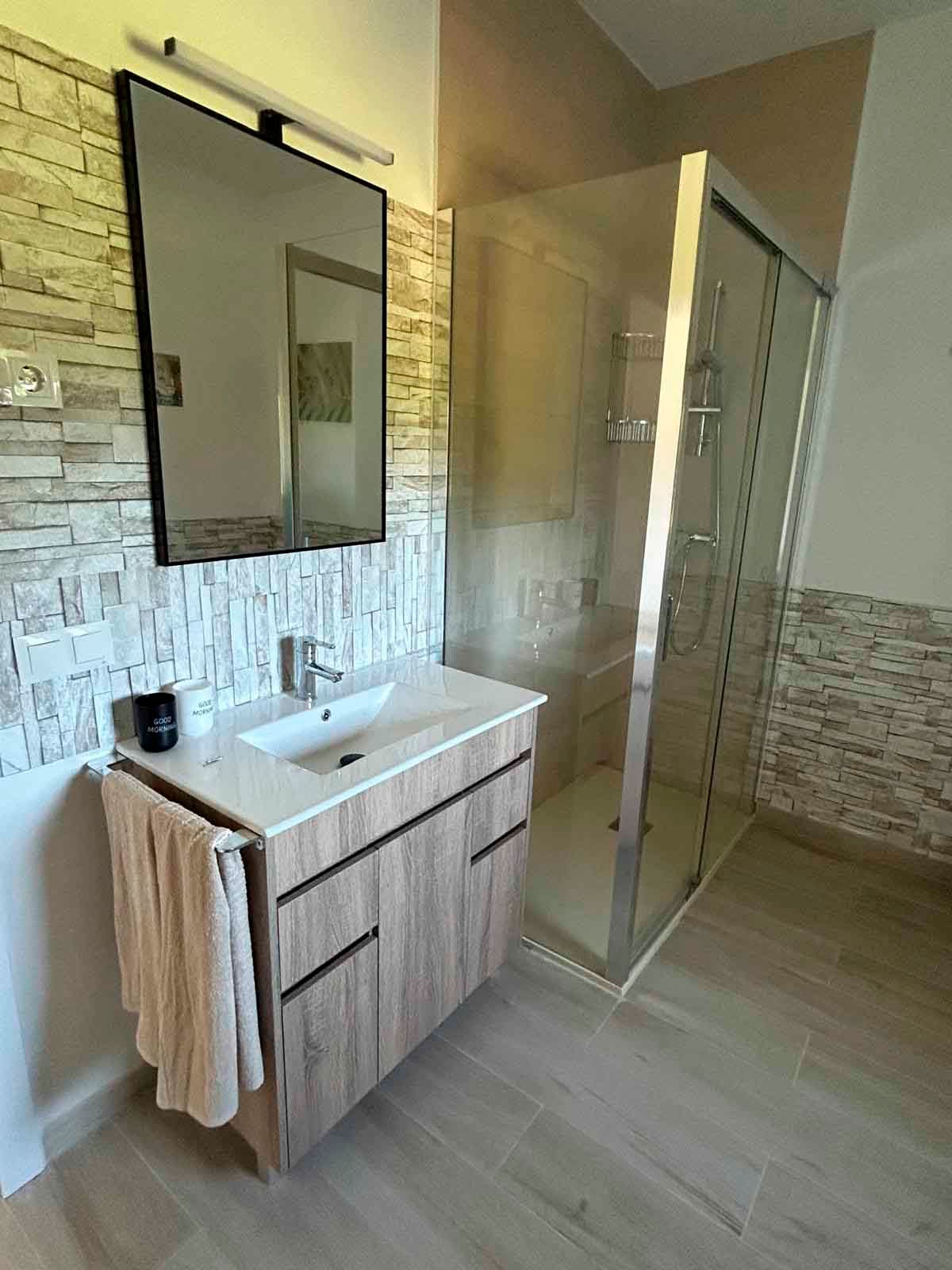 Un baño con lavabo, espejo y ducha.