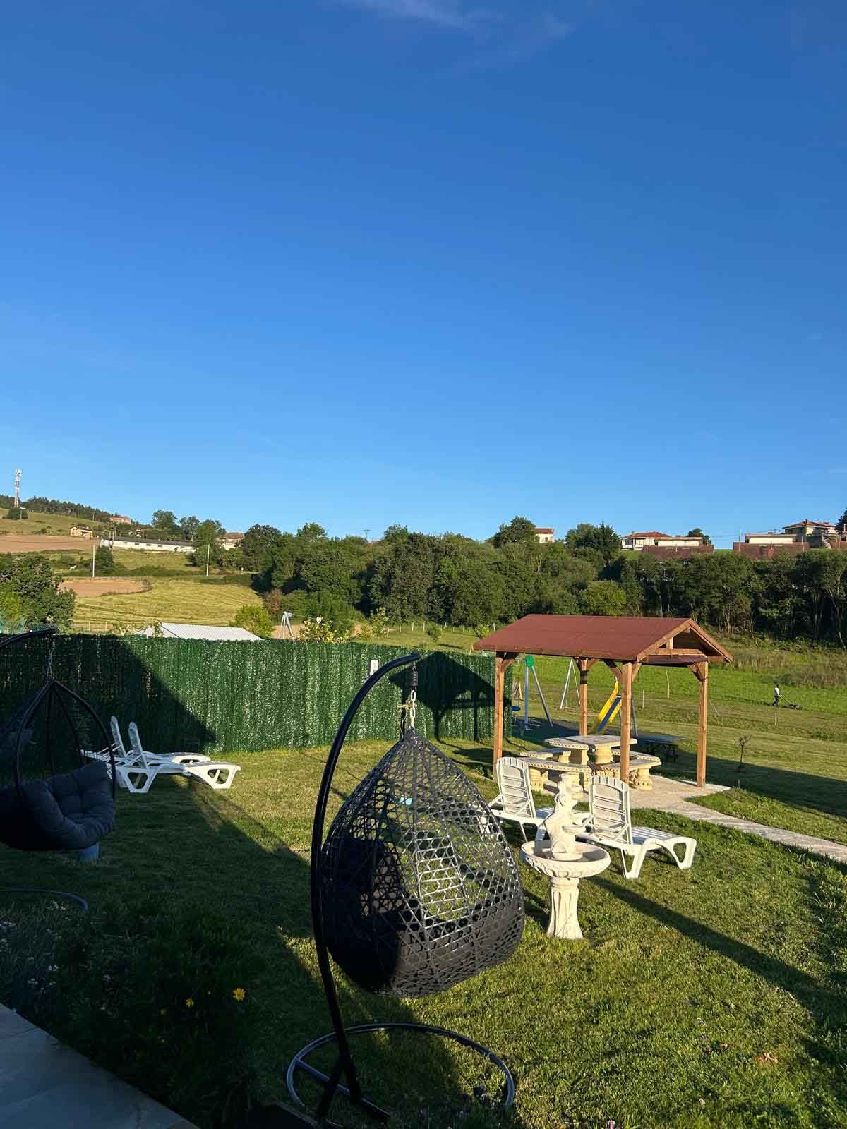 Un césped con un cenador y sillas.