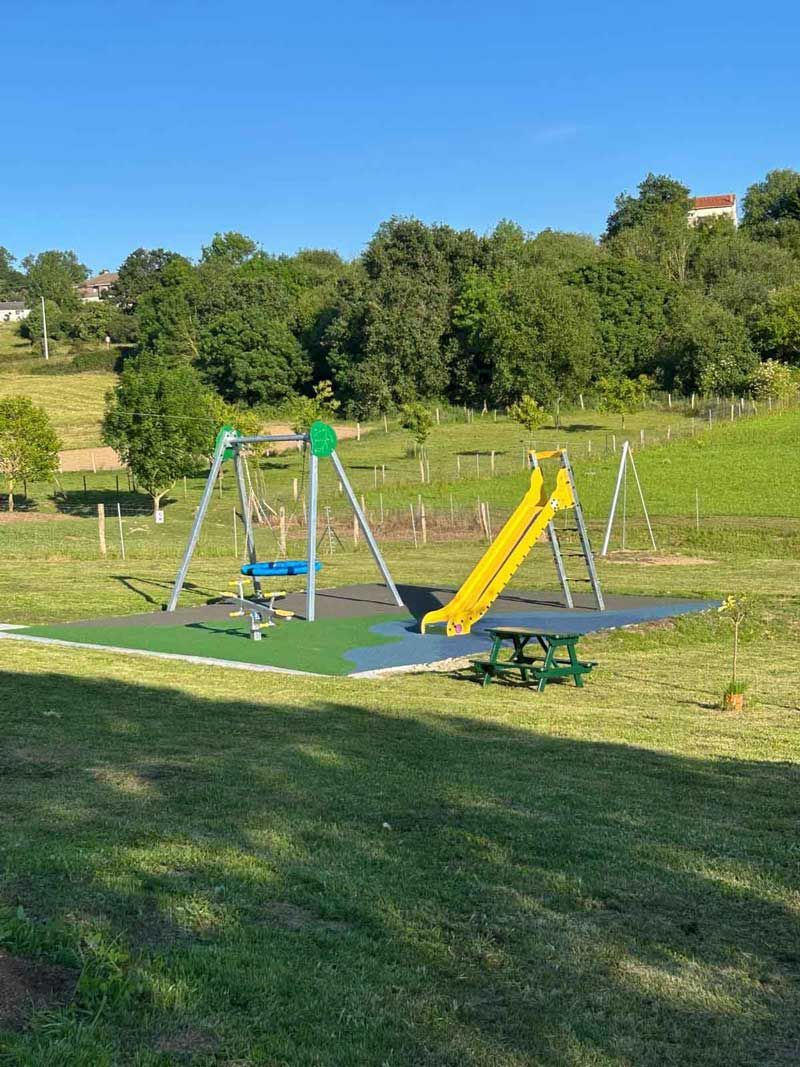 Un patio de juegos con tobogán y columpios en un parque.