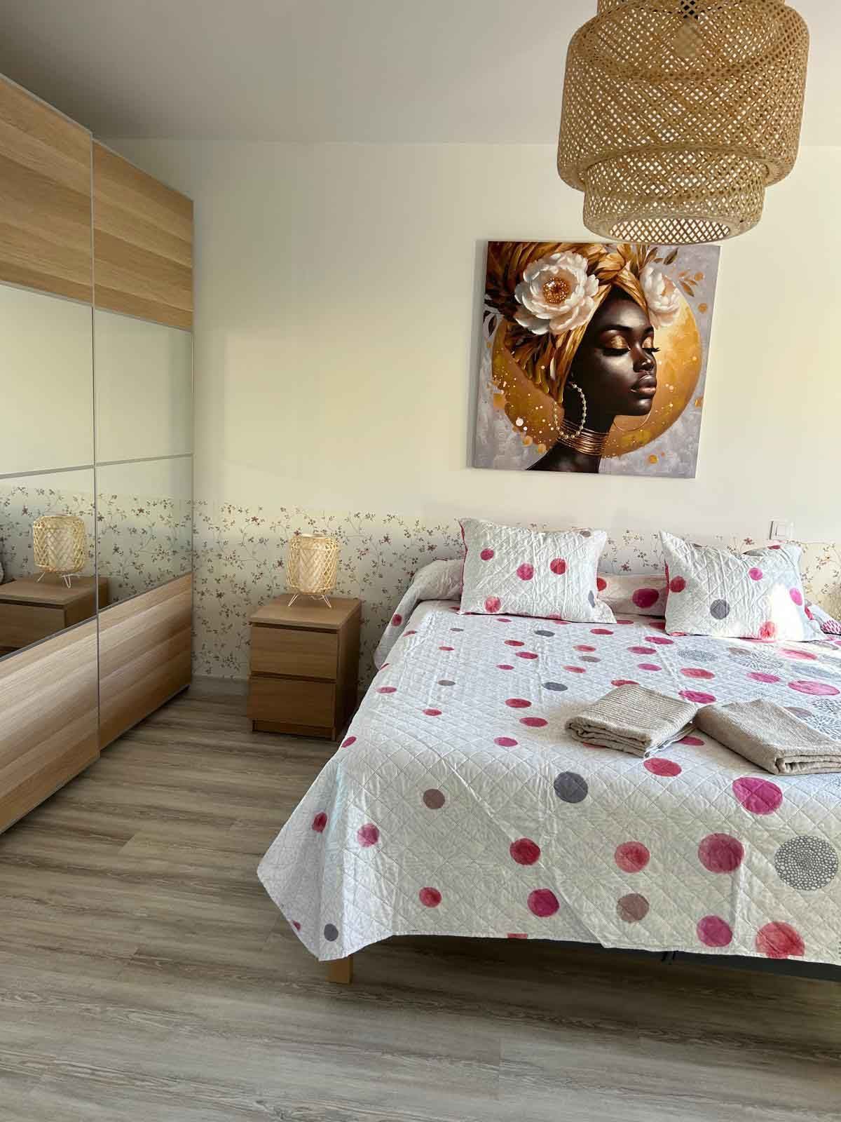 Hay un cuadro de una mujer en la pared encima de la cama.