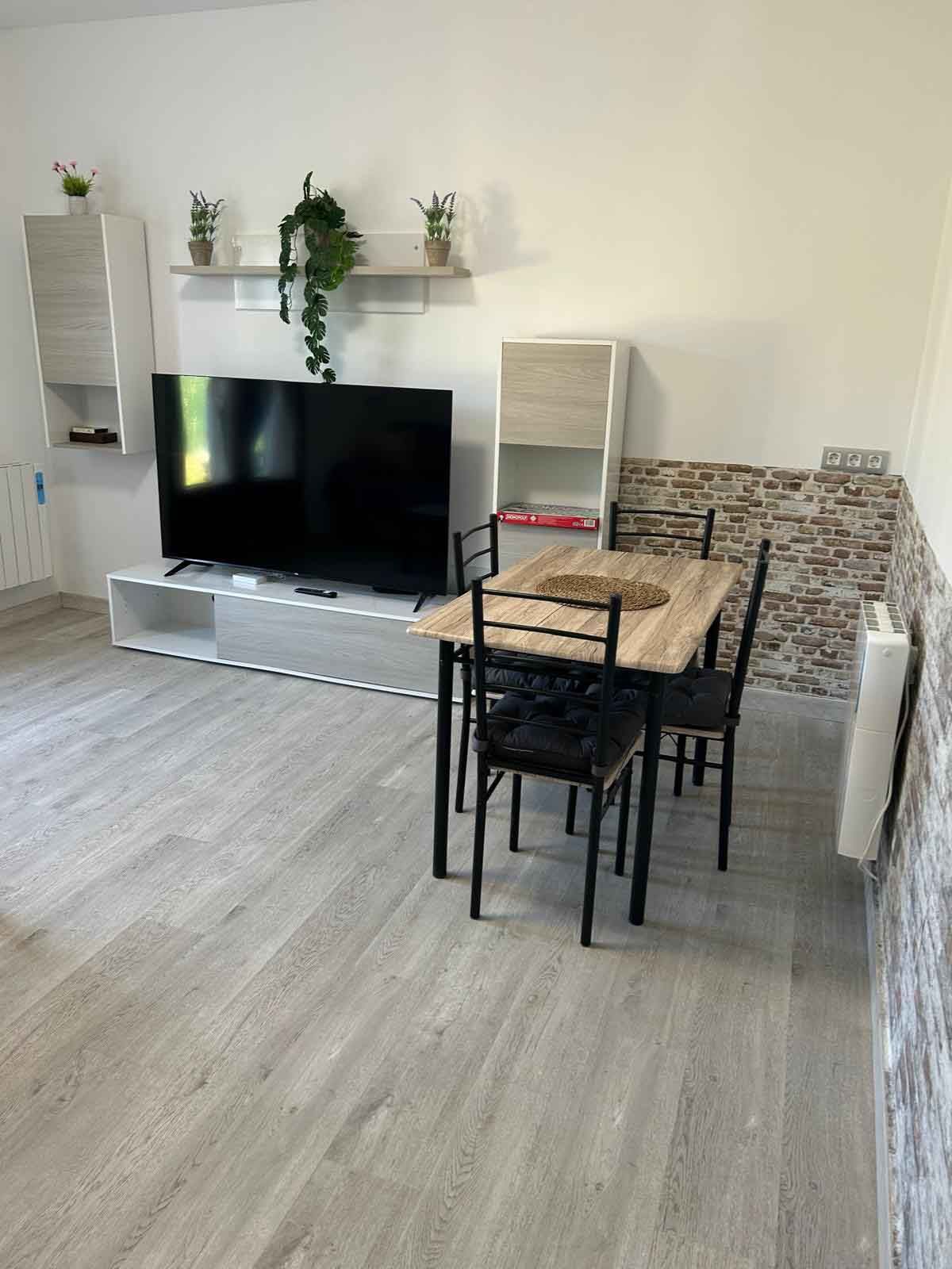 Una sala de estar con una mesa y sillas y un televisor de pantalla plana.