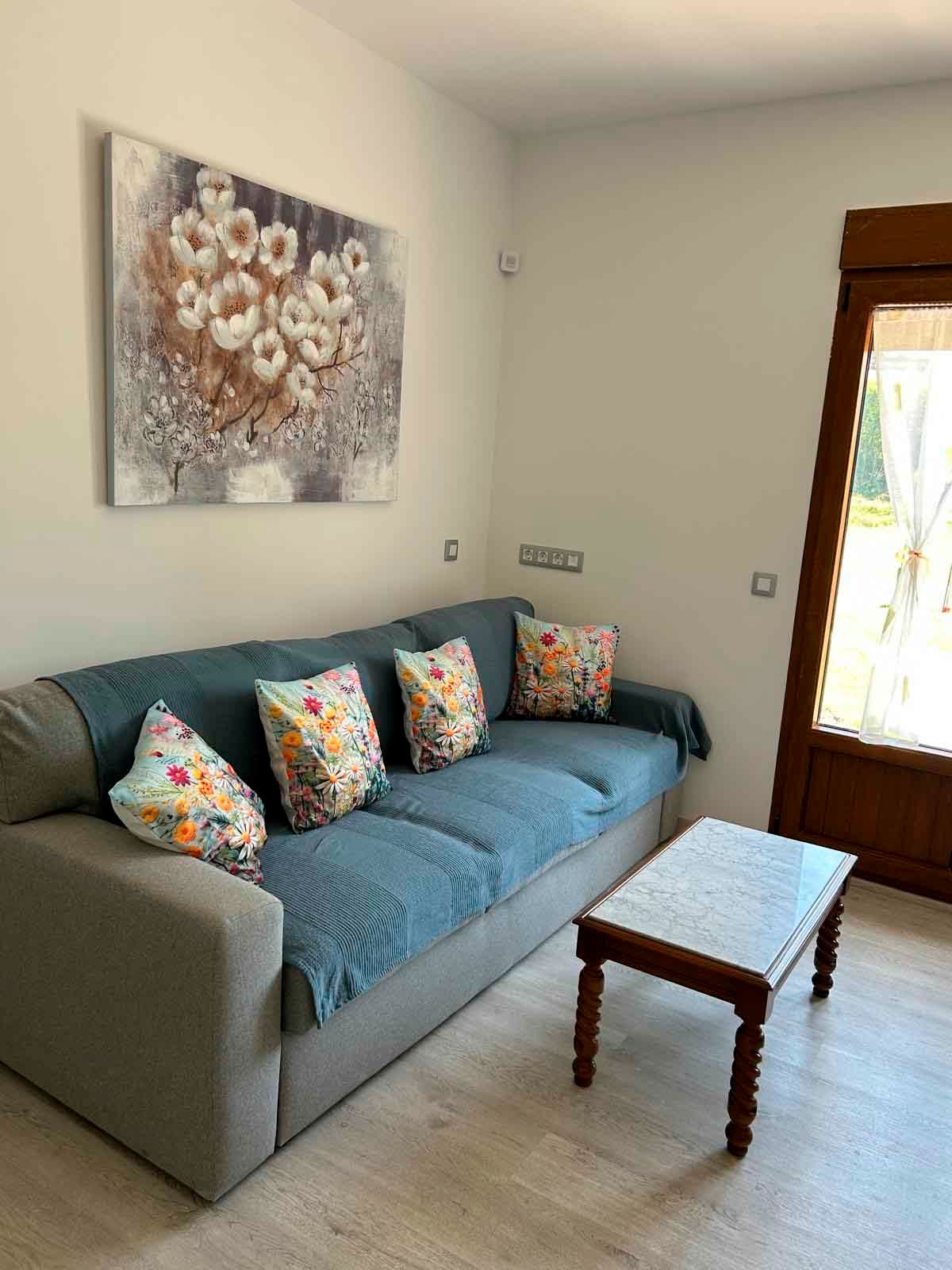 Una sala de estar con un sofá, una mesa y un cuadro en la pared.