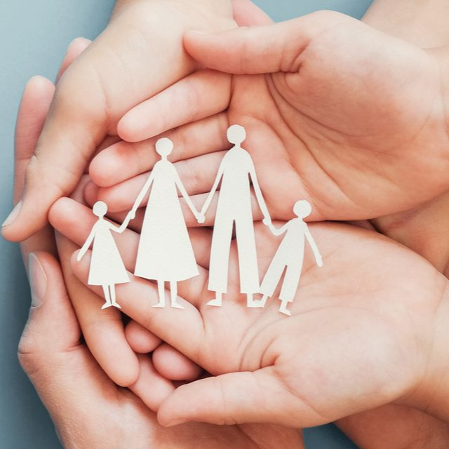 Deux paires de mains jointes tenant une petite silhouette en papier blanc représentant une famille de quatre personnes.