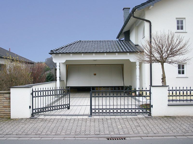 Ein weißes Haus mit einer Garage und einem Zaun
