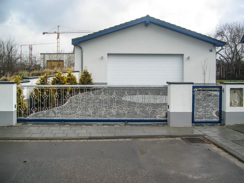 Ein weißes Haus mit blauem Dach und Schiebetor