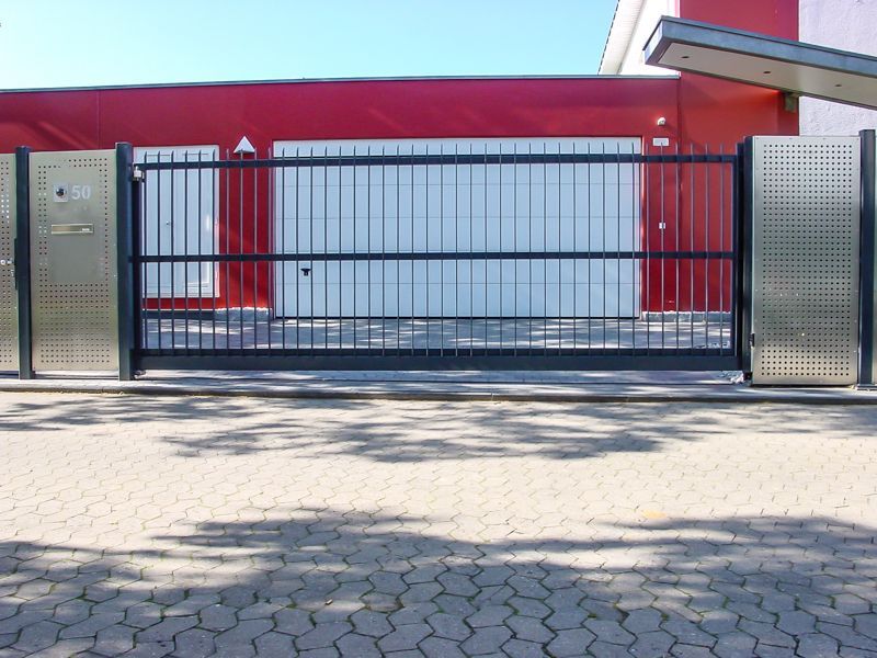 Vor einem roten Gebäude ist ein Schiebetor geöffnet