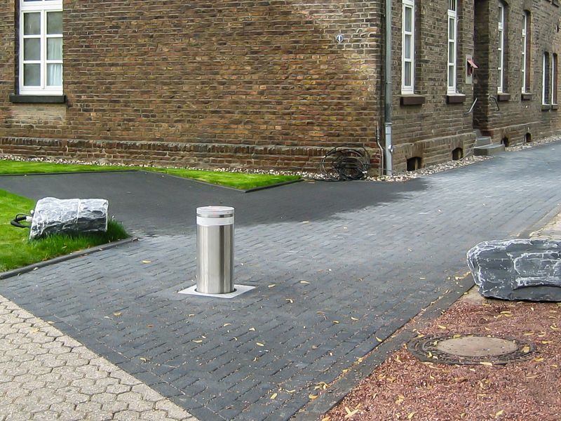 Ein Backsteingebäude mit einer Auffahrt und einem Edelstahlmast