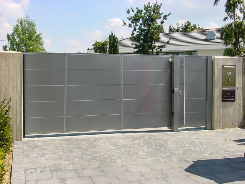 Ein graues Tor ist zu einer Einfahrt vor einem Haus geöffnet