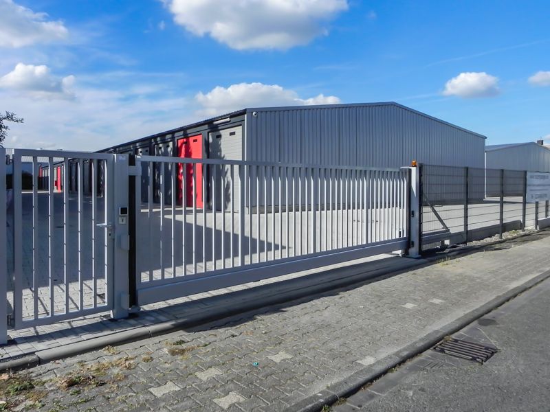 Ein Zaun mit Schiebetor vor einem Gebäude