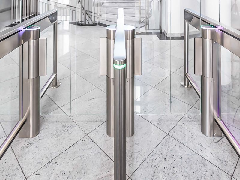 Eine Reihe von Edelstahltoren in einem Flur mit einer Treppe im Hintergrund.