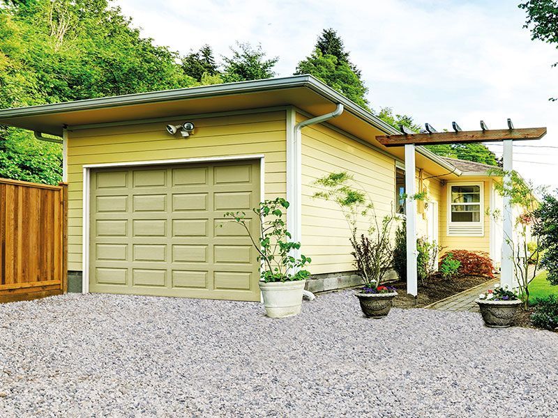 Ein gelbes Haus mit einer Garage und einer Kiesauffahrt