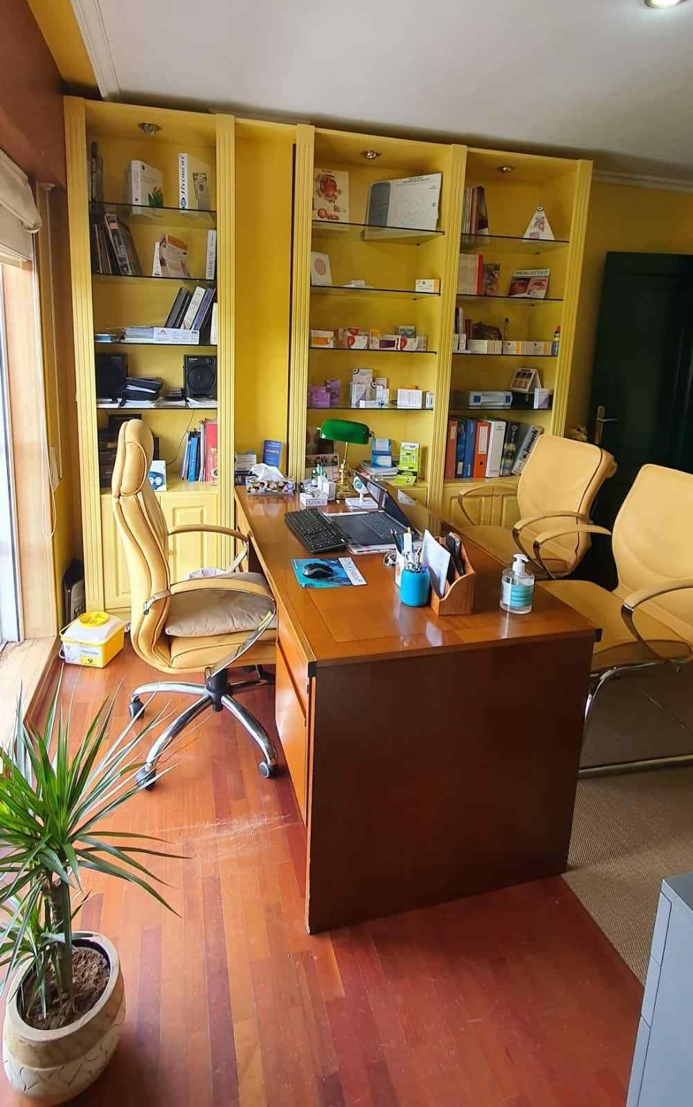 Estanterías empotradas de color amarillo detrás de un escritorio de madera en una pequeña oficina o estudio.