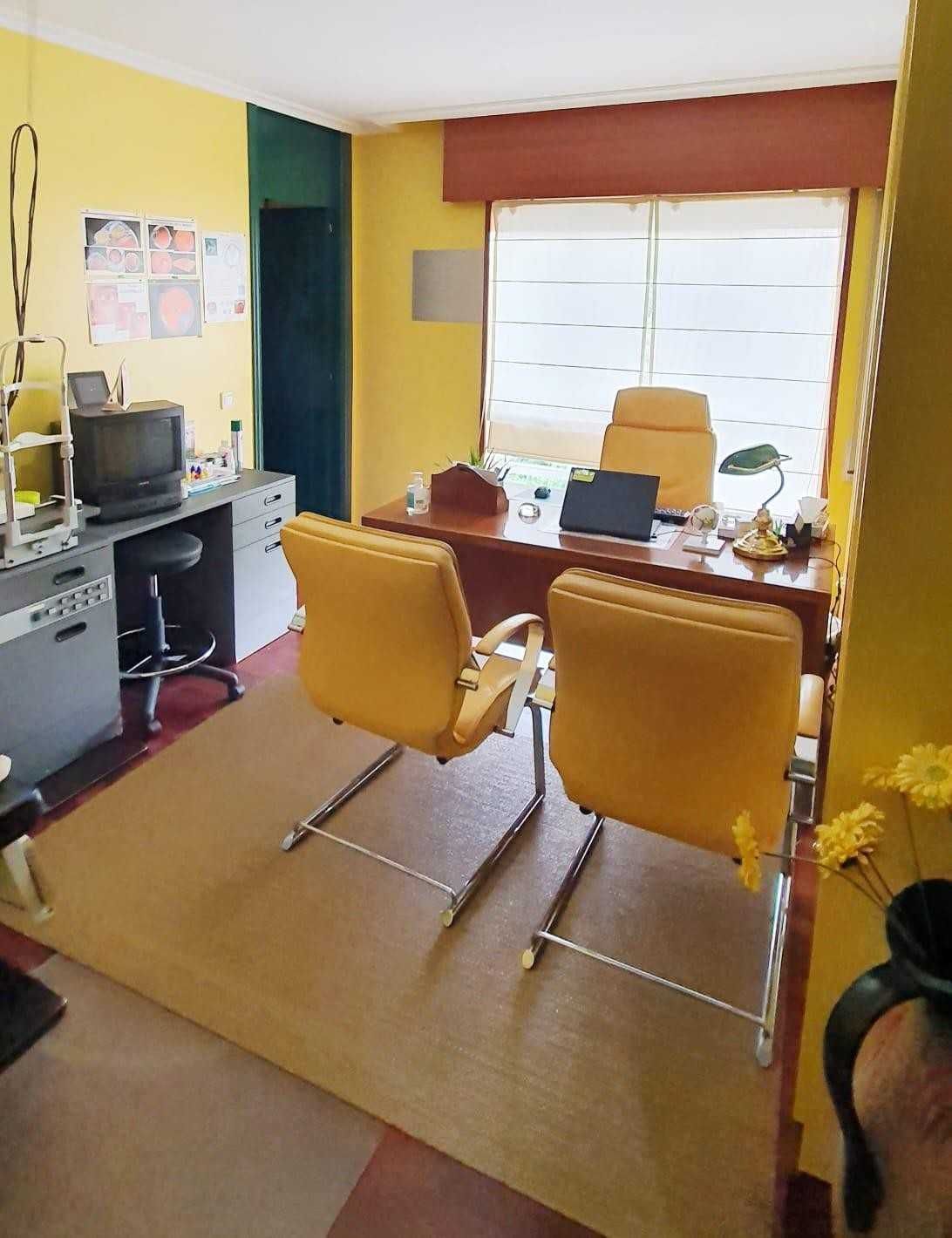 Oficina amarilla con escritorio, dos sillas, ordenador y persianas de colores vivos.