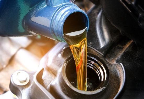 Se vierte una botella de aceite en el motor de un automóvil.