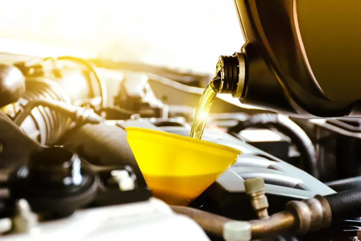 Un primer plano de una persona vertiendo aceite en el motor de un automóvil.