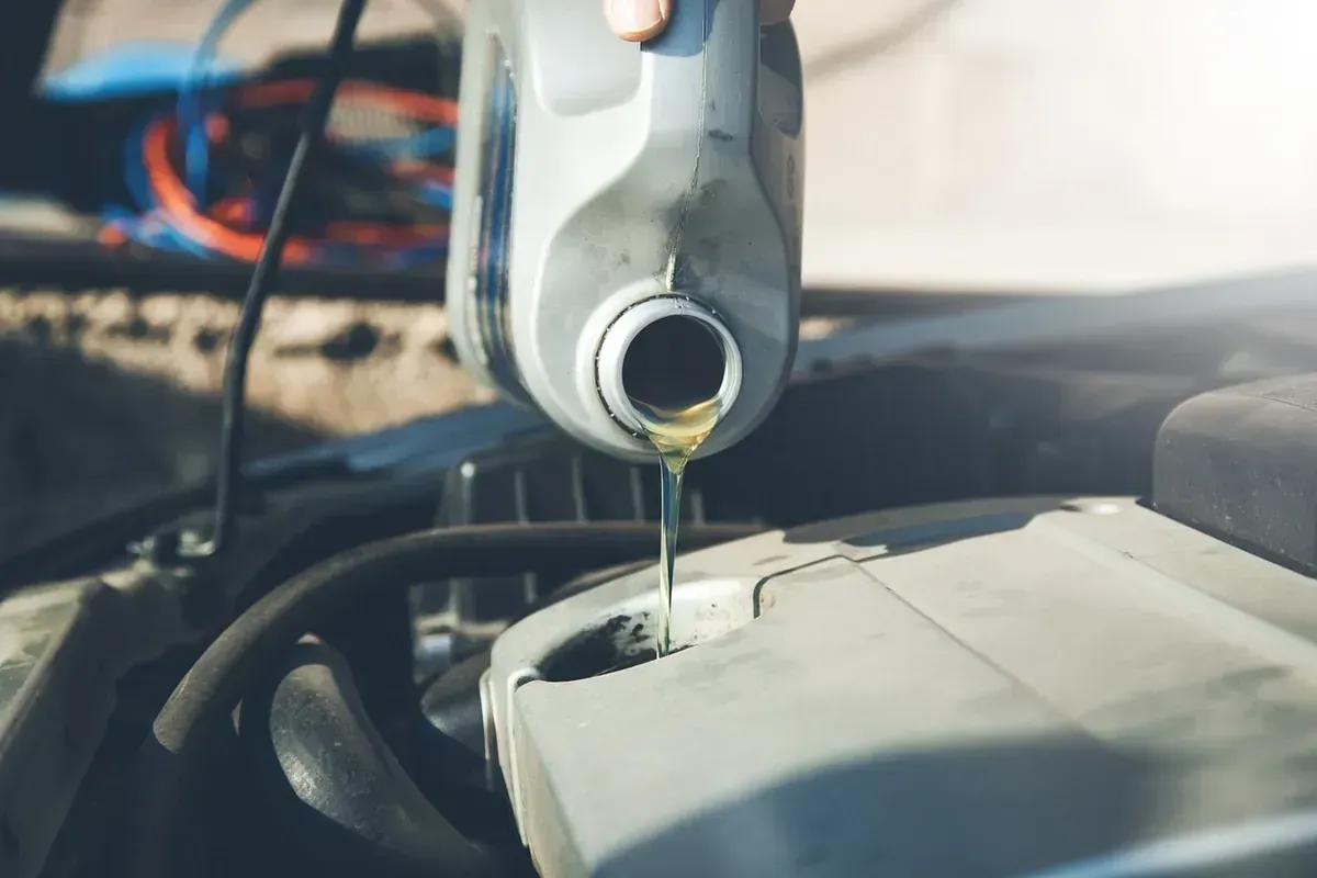 Una persona está vertiendo aceite en el motor de un automóvil.