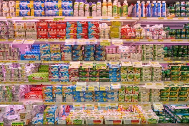 Estantes repletos de coloridos aperitivos y bebidas envasados ​​en un pasillo de un supermercado.