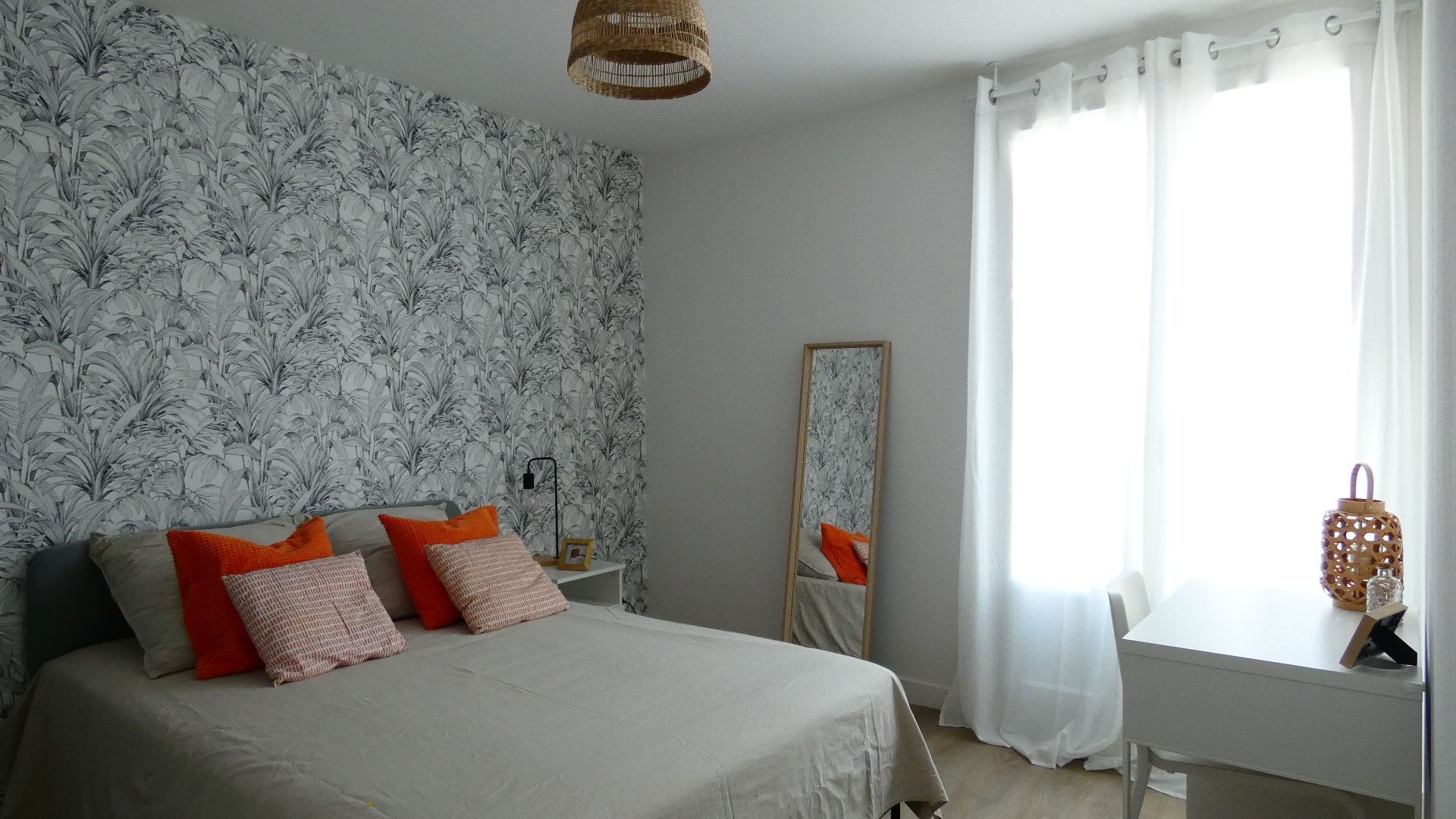 Salon avec canapés gris, table blanche dressée pour quatre personnes et grand miroir.