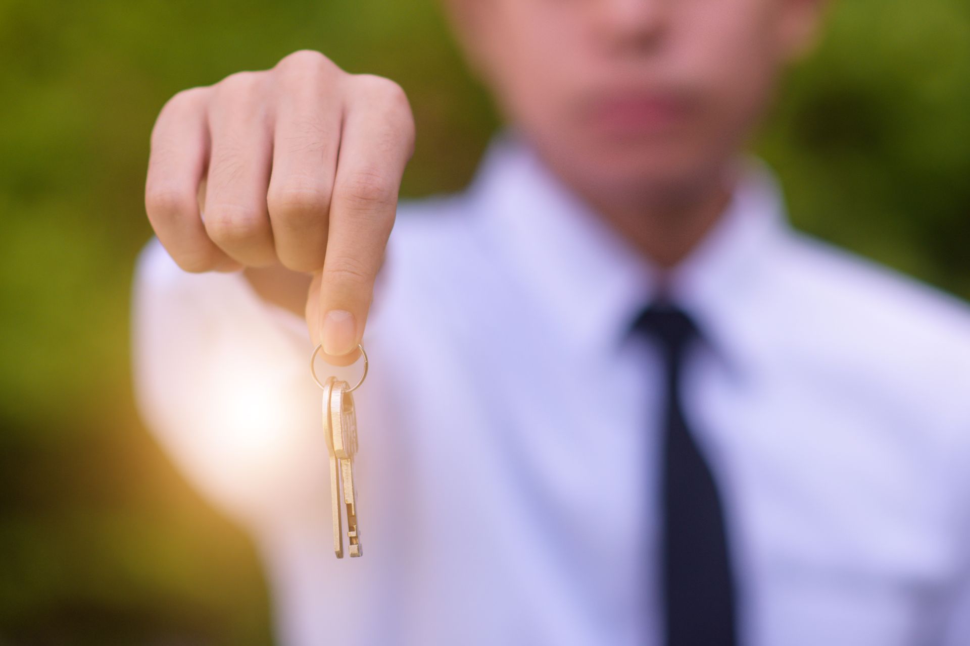 Personne en chemise blanche et cravate tendant des clés.