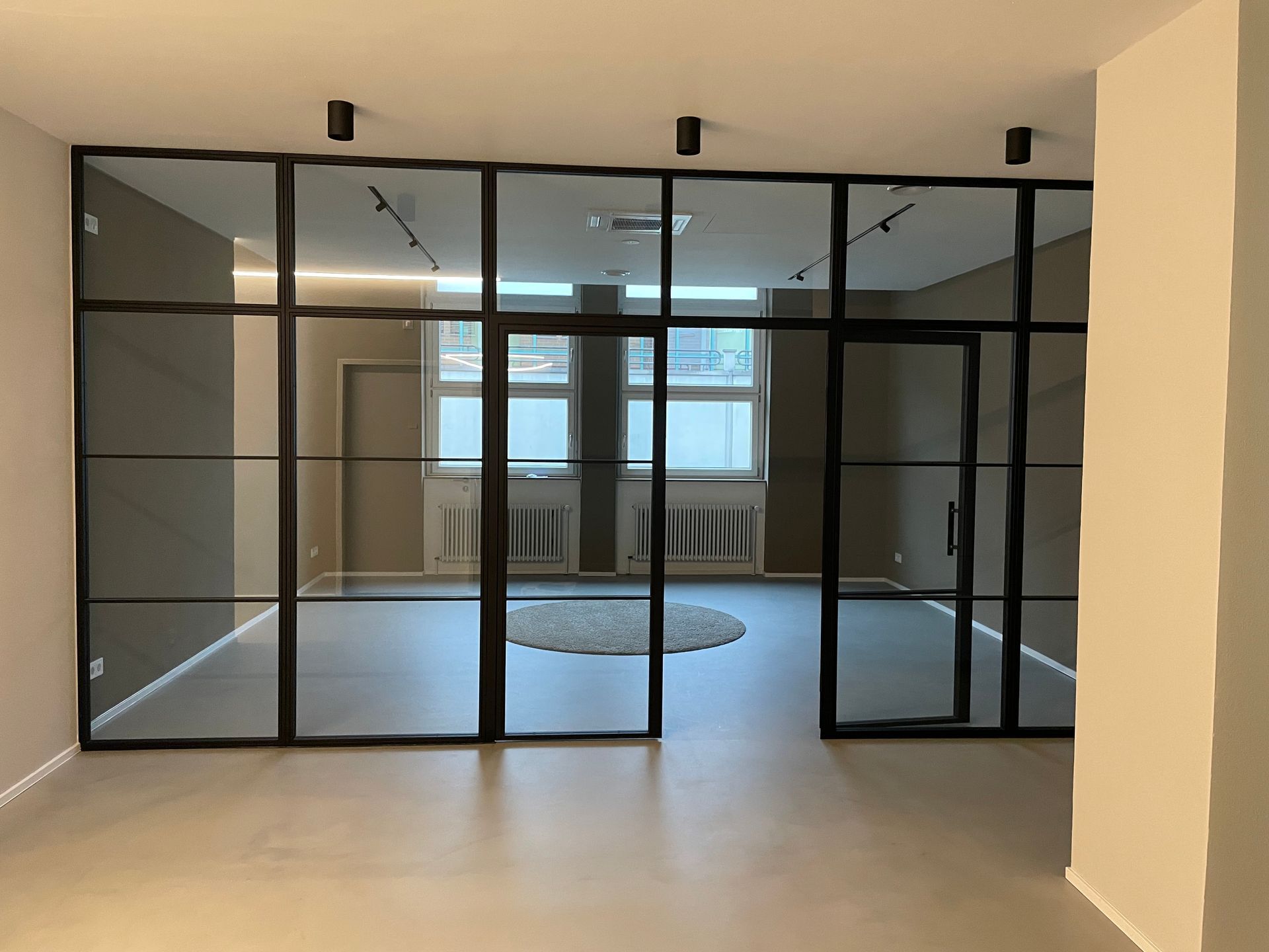 Großzügiges Wohnzimmer mit Kamin, Sofas, großen Fenstern und Parkettboden.