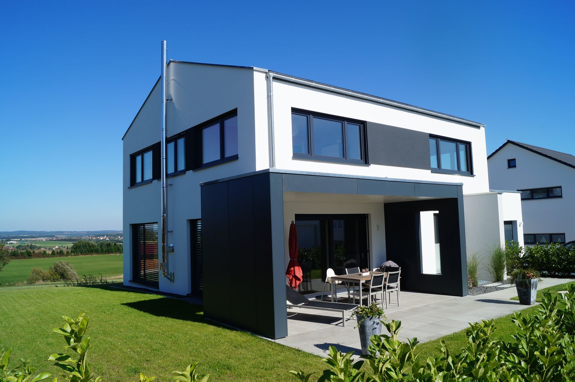 Haus im Bau, Betonrahmen, Dachstützen, Baumaterialien und ein Sonnenuntergangshimmel.