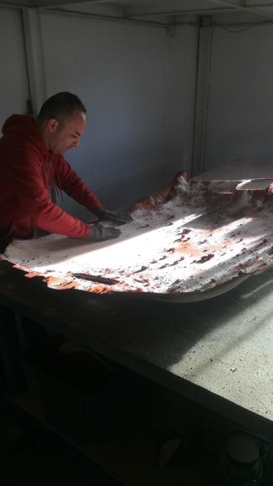 Homem examinando um objeto grande e de formato irregular sobre uma mesa