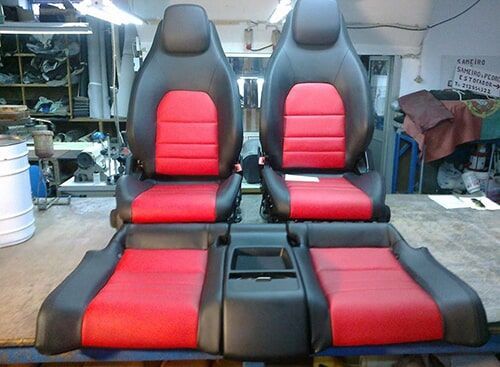 Bancos de carro em couro preto e vermelho, dispostos para montagem.