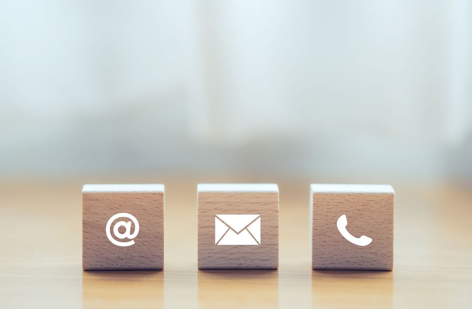 Trois blocs de bois avec des icônes blanches d'e-mail, d'enveloppe et de téléphone.