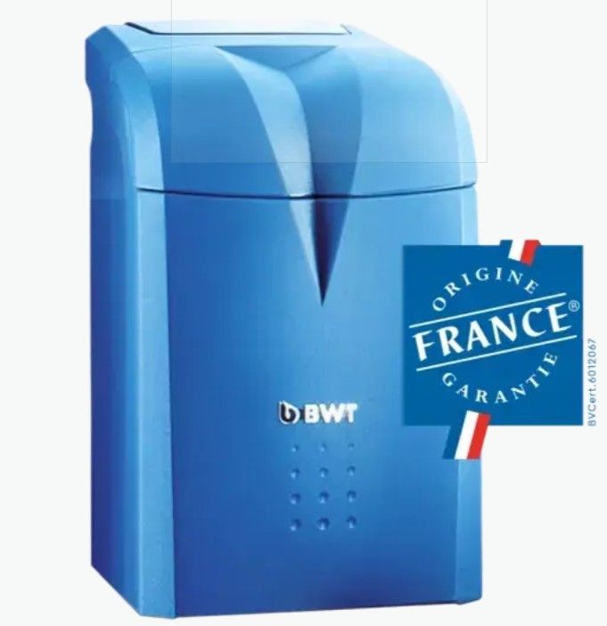 Équipements de plomberie et chauffe-eau muraux dans une buanderie lumineuse avec tuyaux et vannes rouges/bleues.