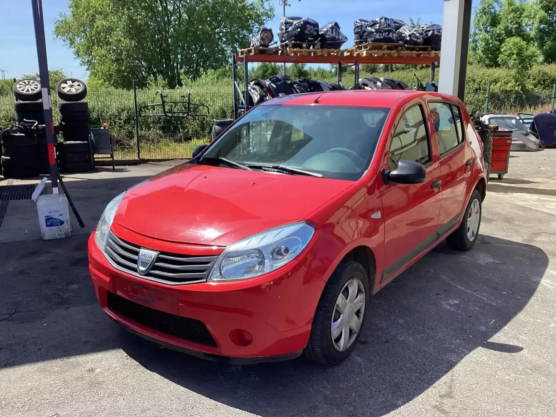 Coche hatchback Dacia Sandero de color rojo en un depósito de chatarra