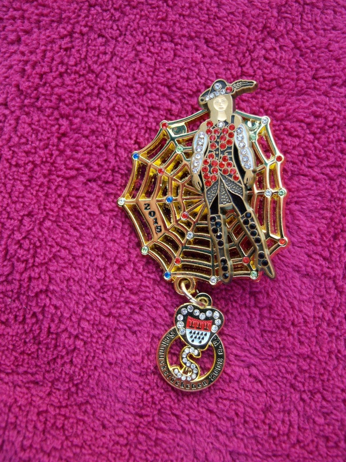 Eine Brosche mit einem Cowboy auf einem Spinnennetz und dem Wort „back“ darauf