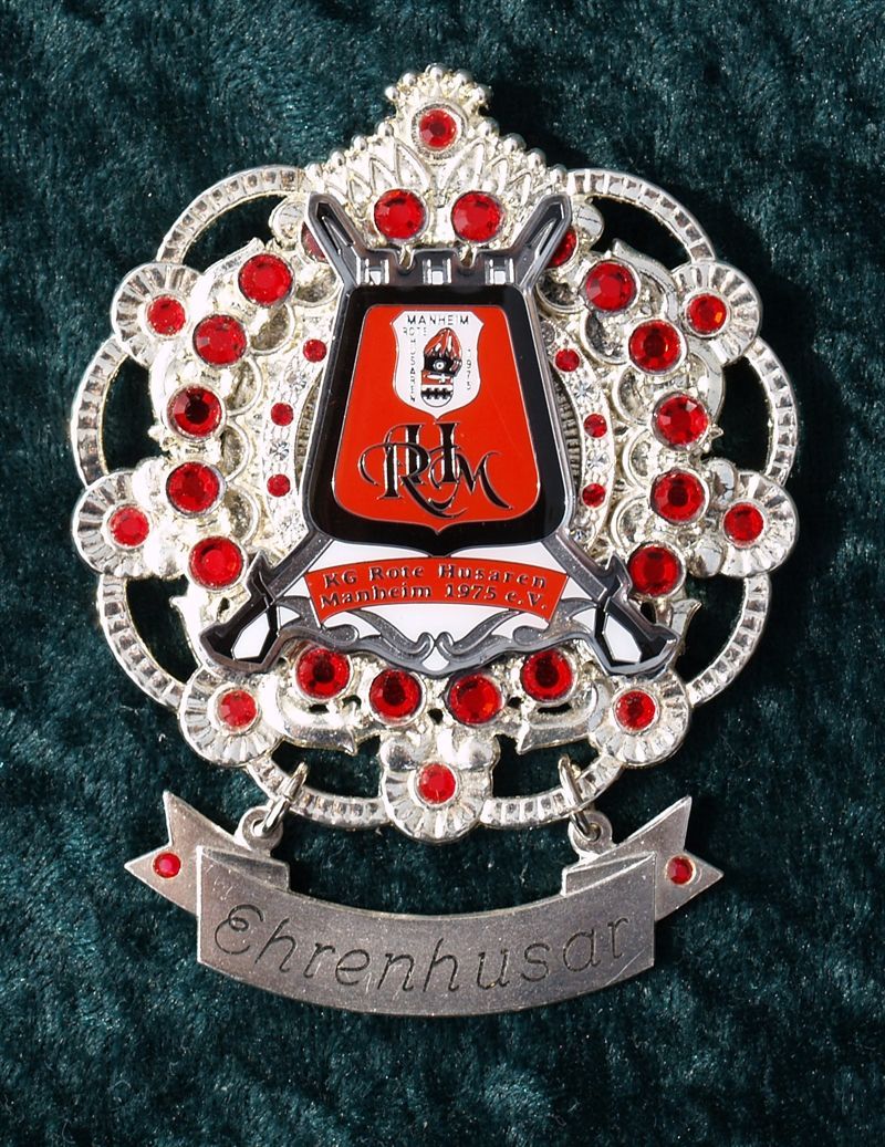 Eine silber-rote Brosche mit dem Wort Ehrenhuern darauf