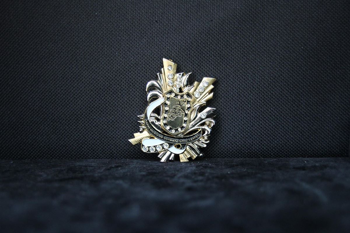 Eine Brosche liegt auf einer schwarzen Oberfläche