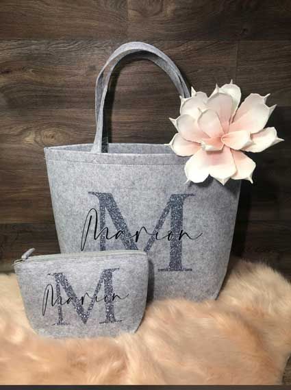 Eine graue Einkaufstasche mit dem Buchstaben M liegt auf einer Plüschdecke.