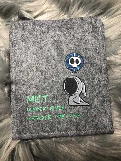 Ein graues T-Shirt mit einem Luftballon darauf liegt auf einer pelzigen Oberfläche.