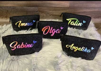 Eine Gruppe Kosmetiktaschen mit Namen darauf liegt auf einem Fellteppich.