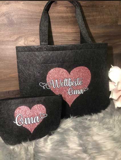Eine schwarze Einkaufstasche mit einem rosa Herz darauf liegt auf einem Holztisch.