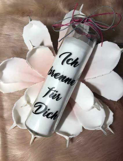 Eine weiße Kerze steht auf einem Blütenblatt.