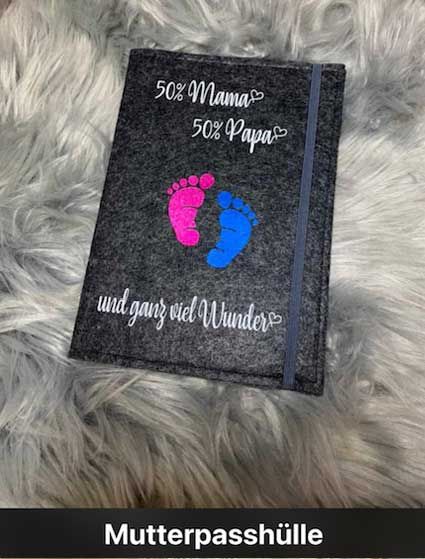 Eine Mutterpasshülle mit einem rosa-blauen Fußabdruck darauf.