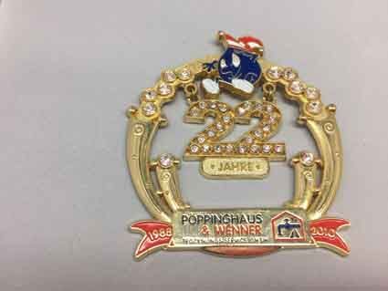 Eine goldene Anstecknadel mit einer Comicfigur darauf liegt auf einer weißen Oberfläche.