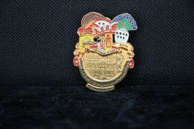 Auf einer schwarzen Fläche liegt ein goldenes Abzeichen mit einem Gesicht darauf.