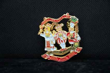 Auf einer schwarzen Oberfläche liegt eine Brosche mit drei Comicfiguren.