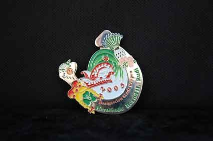 Eine bunte Anstecknadel mit einer Schildkröte darauf liegt auf einer schwarzen Oberfläche.