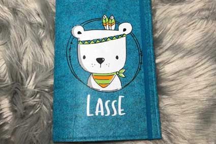 Ein blaues Buch mit einem Bären auf dem Einband liegt auf einer pelzigen Oberfläche.