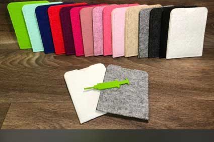 Auf einem Holztisch liegen mehrere verschiedenfarbige Filzstücke.