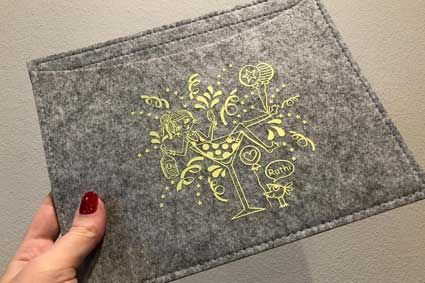 Eine Person hält ein Tischset mit einem Martini-Glas darauf.