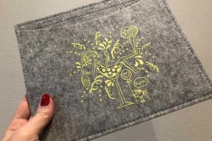 Eine Person hält ein Tischset mit dem Bild eines Weinglases darauf.