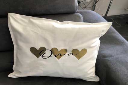 Auf einem Sofa liegt ein weißes Kissen mit goldenen Herzen darauf.