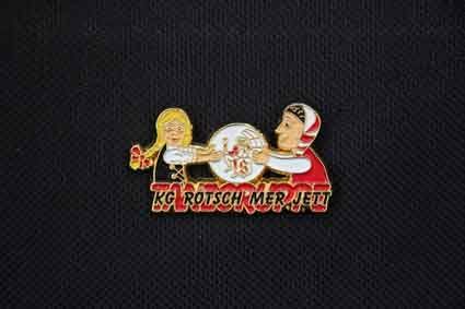 Eine Anstecknadel mit einem Jungen und einem Mädchen darauf auf schwarzem Hintergrund.